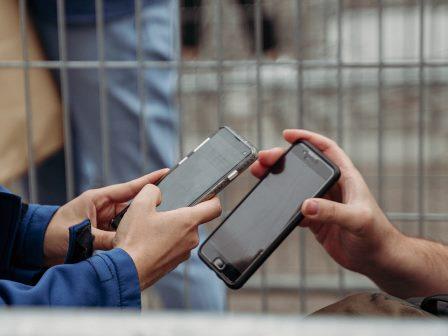 Foto primo piano delle mani di due persone che affiancano i loro smartphone per confrontare qualcosa